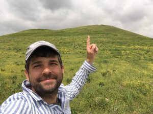 John Christopher Frame pointing to a grassy mount (Lystra)